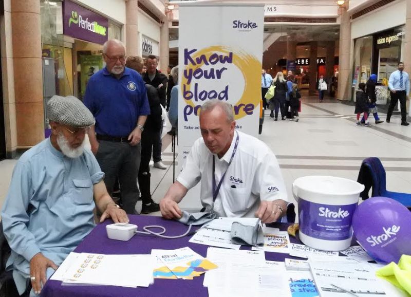 The picture shows Steve Bowden from Oldham Stroke Association measuring a shopper’s blood pressures with secretary of Rotary Club of Chadderton & Failsworth, Tony Wright in the background