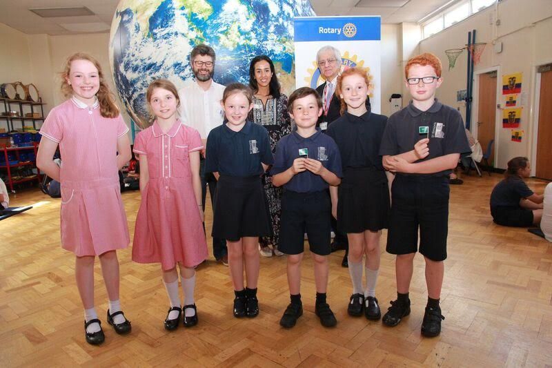 from L to R, Sam Harris of the Manchester International Society, one of the volunteer international postgraduate students and Najib Yousif of the Rotary Club of Stockport Lamplighter with children from St Simon's Catholic Primary School in Hazel Grove