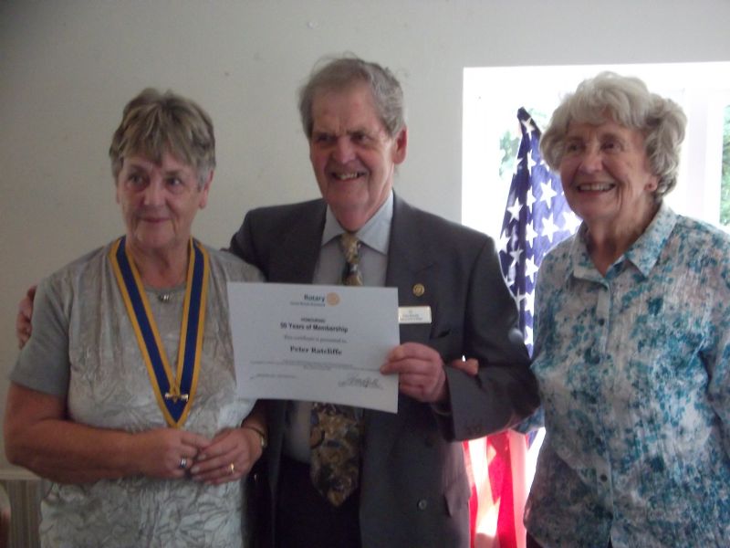 Photo of President Gwyneth Millard  and Peter Ratcliffe with his wife Jean at his side receiving his Long Service of 50 years Certificate