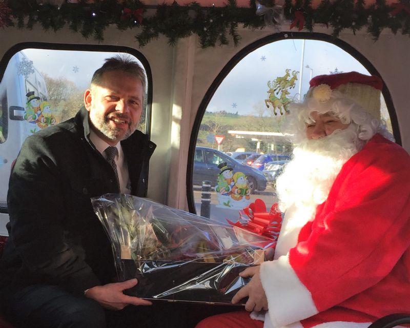 The attached photo shows: Allan Pyatt from Mc Gough & Sons Funeral Directors, receiving the Christmas Hamper  which is presented to the winner of the draw between the donors who sponsor the Sleigh.