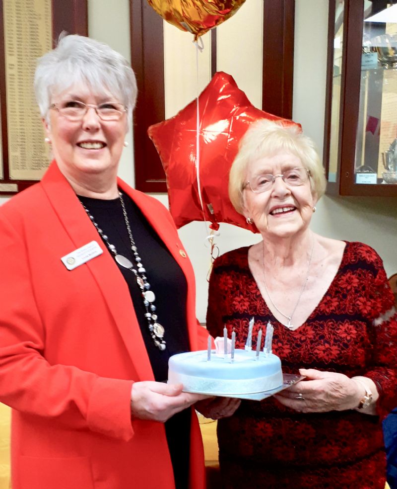 Linda Mullins ( left ) presents a birthday cake to Joan Ebbrell ( right )