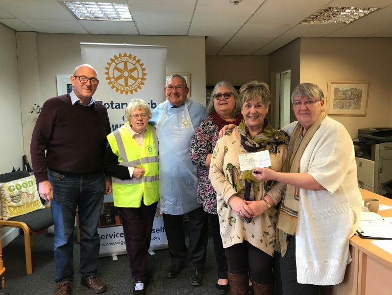 Barbara  Nettleton  at Sunshine House receiving a cheque from Wigan Rotary club members and President Gwyneth Millard  during the day while Wigan Rotary were collecting the surplus medical equipment